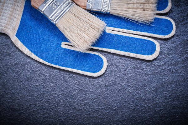 Paint brushes safety gloves on black surface construction concept