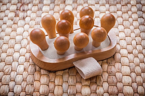 Single wooden massager with rubber band on wicker mat Healthcare concept