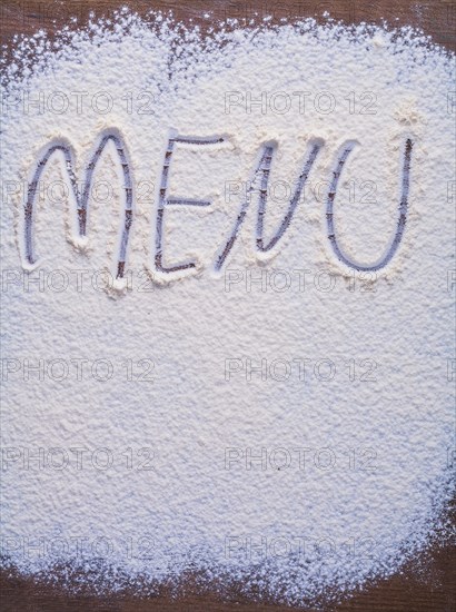 Handwritten inscription menu is made with flour on vintage wooden table vertical version food and drink concept