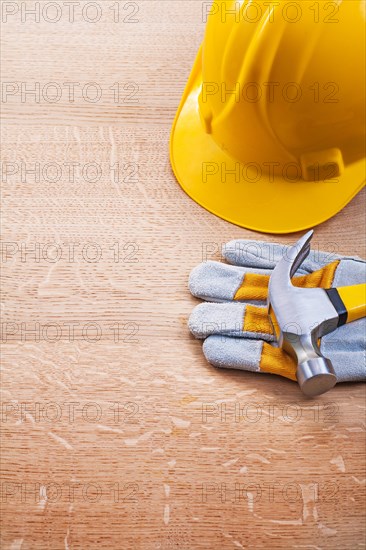 Yellow helmet Protective glove Claw hammer on wooden board Construction concept