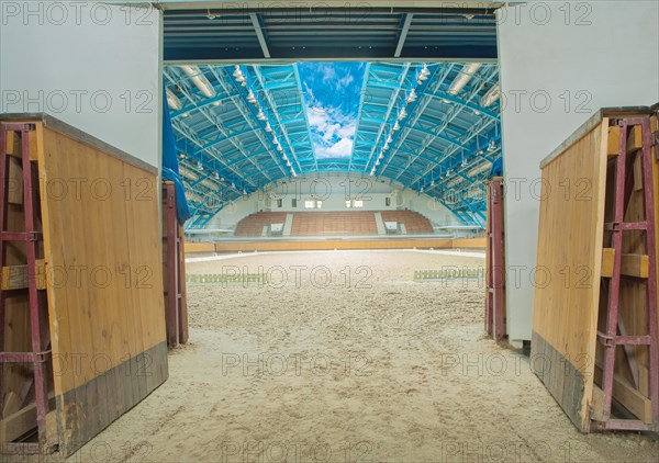 Empty large indoor riding arena with open sky