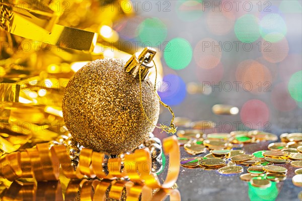 Gold coloured christmas ball with string on background of bokeh horizontal version