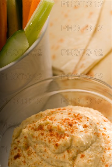 Middle eastern hummus dip on a glass bowl with homemade pita bread and raw vegetable