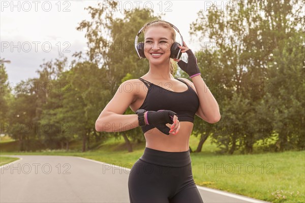 Charming girl in headphones stands in the park after jogging