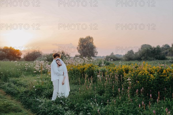 Loving couple of newlyweds at sunset in the field