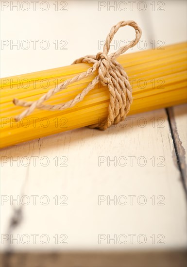 Italian pasta spaghetti tied with a rope on a rustic table