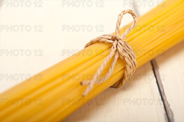 Italian pasta spaghetti tied with a rope on a rustic table