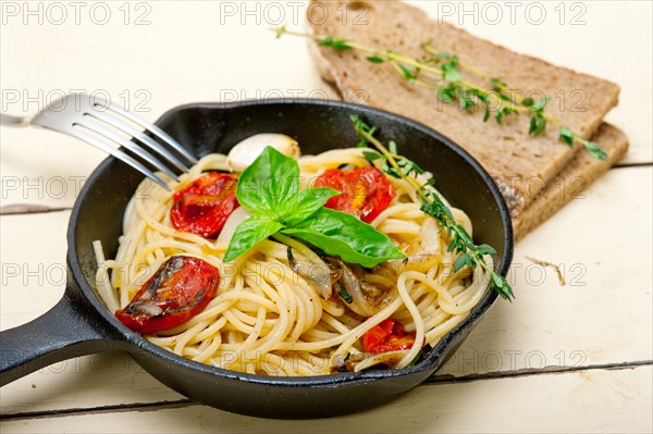 Italian spaghetti pasta with baked tomatoes basil and thyme sauce on a cast iron skillet