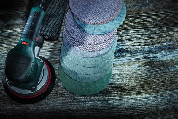 Electric orbit wood sander with sanding discs on dark vintage wooden background