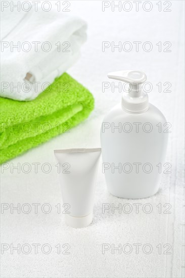 Bottle tube and towels on white background