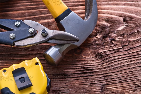 Metal claw hammer pliers and adhesive tape line on wooden board Construction concept