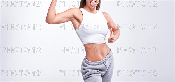 No name portrait. Young white fitness woman wearing sportswear standing over white wall background. Fitness concept. Mixed media