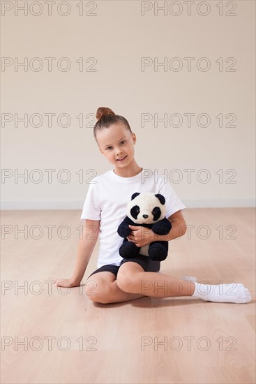 Cute girl child posing in the studio with a soft toy in a light studio. The concept of education