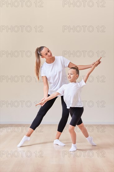 Beautiful woman teacher and a little girl perform dance movements in a bright studio. The concept of education