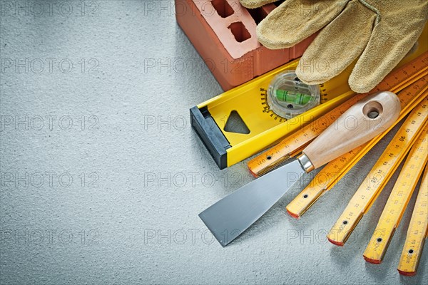 Red brick working gloves plastering trowel construction level wooden meter on concrete background bricklaying concept