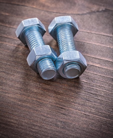 Steel stainless steel threaded bolts and nuts on vintage brown wooden board repair concept