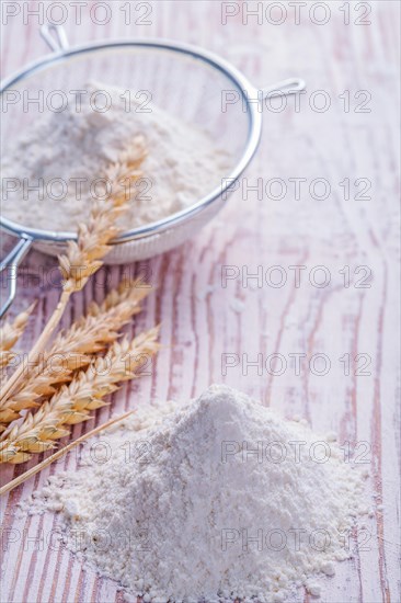 Wheat ears and flour in a needle on an old wooden table