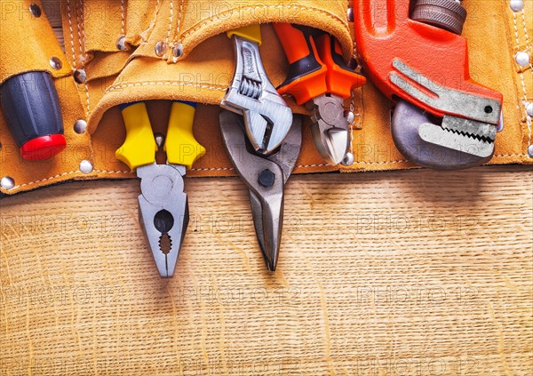 Spanner pliers Steel pliers Screwdriver in tool belt on wooden board