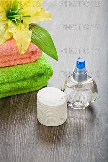 Bottle cloths flower and cotton pads on a wooden background