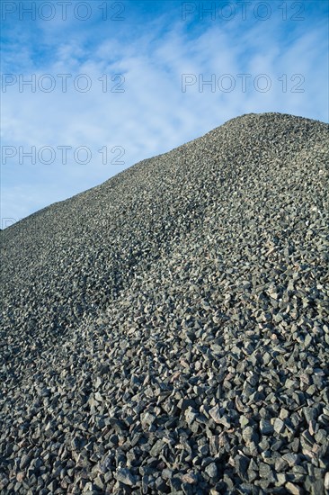Close up view on big pile of grey gravel on background of blue sky