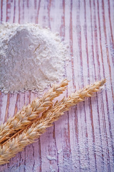 Ears of wheat and flour on a vintage wooden board Food and drink concept