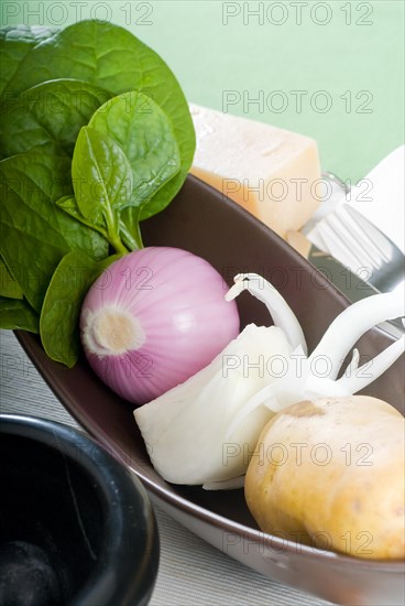 Bowl of fresh vegetable with spice and mortar beside