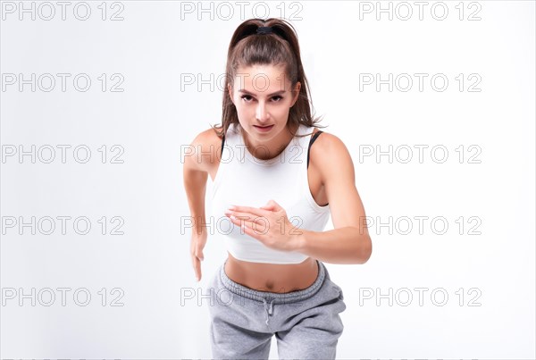 Sports woman runner on a white background. Photo of an attractive woman in fashionable sportswear. Dynamic movement. Side view. Sports and healthy lifestyle. Mixed media