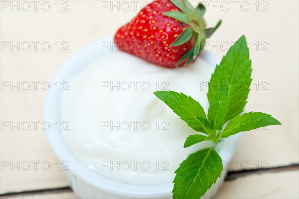 Organic Greek yogurt and strawberry over white rustic wood table
