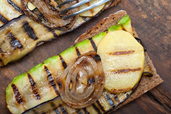 Grilled vegetables on rustic bread over wood table