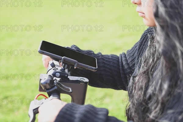 Side view of Beautiful Latina woman with long black hair riding her motorised scooter in the city