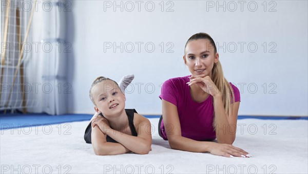 Training in the gym class. A little girl under the guidance of a trainer performs exercises. Gymnastics concept. Mixed media