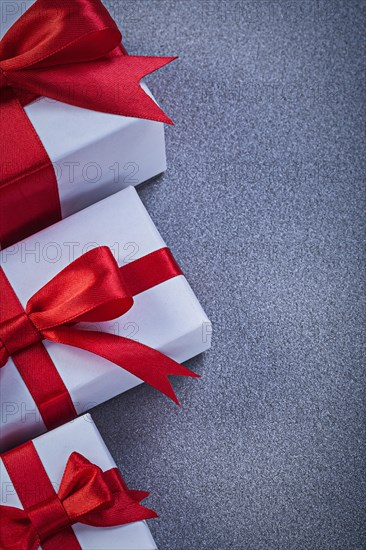 Boxed gifts with tied red bows on grey surface holidays concept