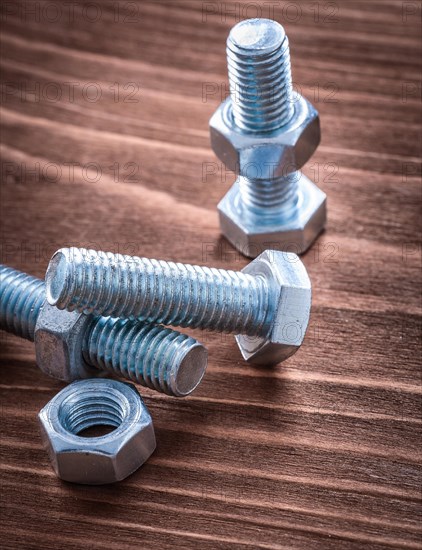 Group of stainless steel threaded bolts and nuts on vintage wooden board construction concept
