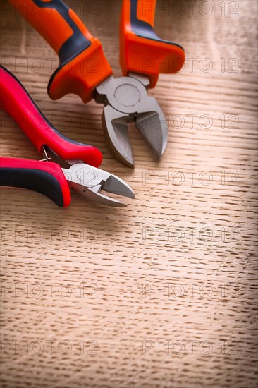 Two pliers up close on a wooden board