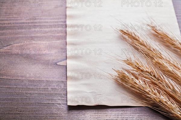 Ears of wheat on vintage blanc paper and old wooden board food and drink concept