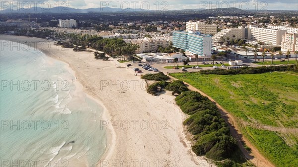 Aerial view of a sunny coastline with waves hitting the sandy shore