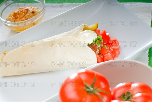 Fresh traditional falafel wrap on pita bread with fresh chopped tomatoes