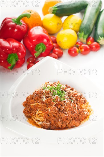 Italian classic spaghetti with bolognese sauce and fresh vegetables on background