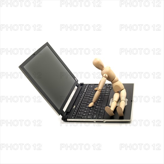 Wood mannequin sitting on a laptop isolated on white background