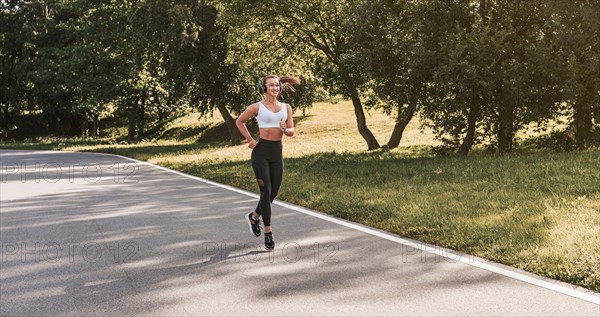 Fitness girl in sportswear runs through the evening sunny park. Healthy lifestyle. Mixed media