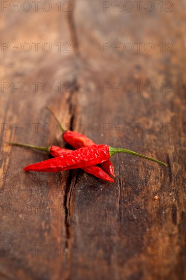 Dry red chili peppers over old wood table