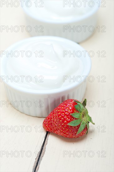 Organic Greek yogurt and strawberry over white rustic wood table