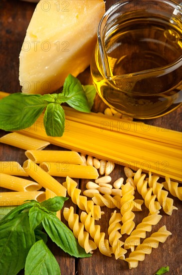 Italian basil pesto ingredients and raw pasta over old wood macro