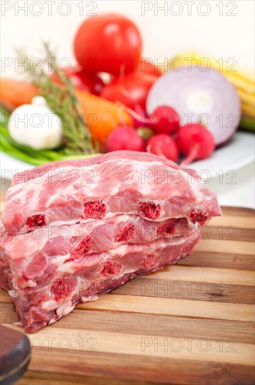 Chopping fresh pork ribs with vegetables and herbs ready to cook