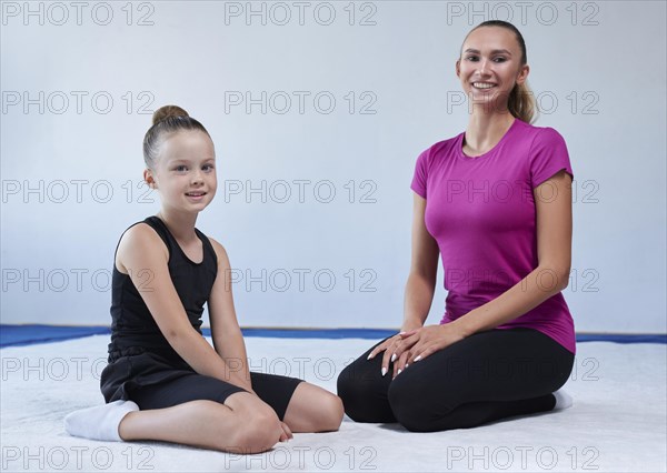 Training in the gym class. A little girl under the guidance of a trainer performs exercises. Gymnastics concept. Mixed media