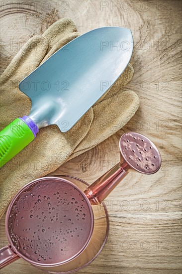 Hand spade pair of working gloves watering can on wooden board gardening concept