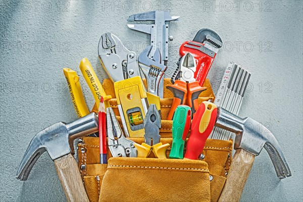 Composition of construction tooling in tool belt on concrete background