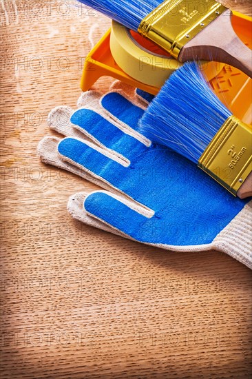 Paint tray Brushes Adhesive tape and protective gloves on wooden panel Construction concept