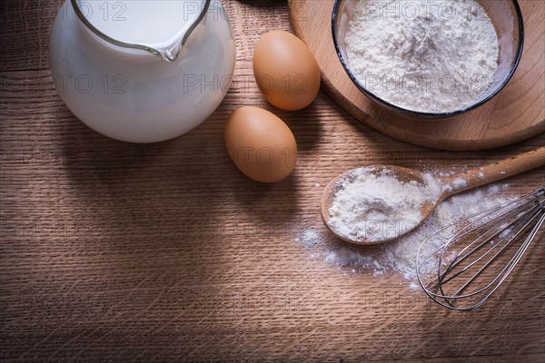 Flour in bowl and spoon Flower crown Egg jug with milk on wooden board Food and drink Still life