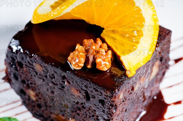 Fresh baked delicious chocolate and walnuts cake with slice of orance on top